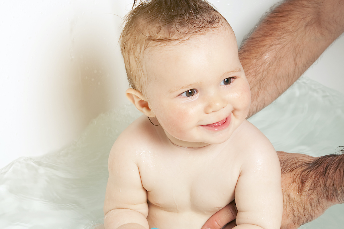 Lächelndes Baby badet in der Badewanne.